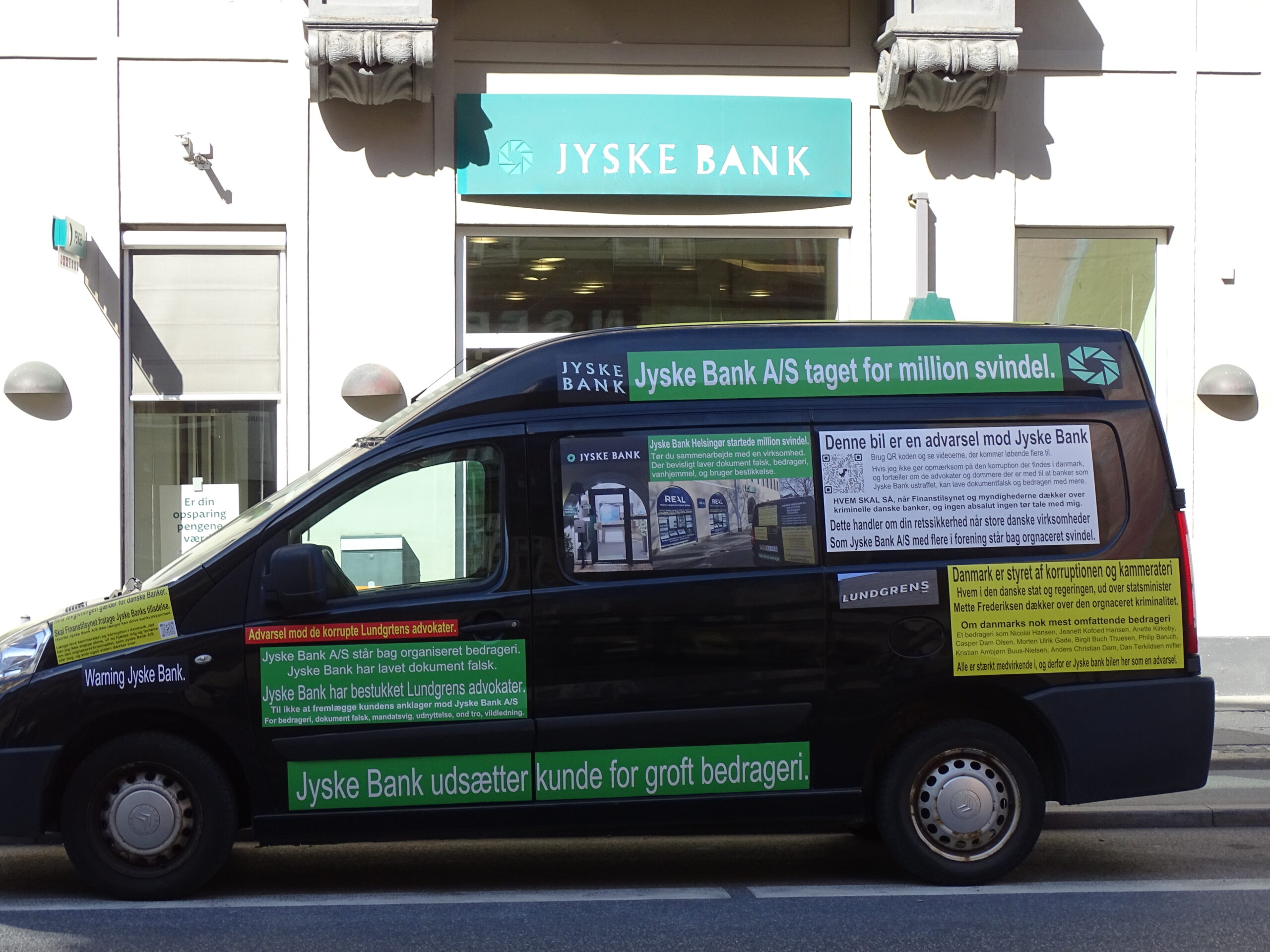 Jyske Bank bilen foran den kriminelle Jyske Bank i Helsingør, reklame for Jyske Banks forretnings metoder Myndighederne i Danmark får alle her i denne mail kraftig kritik 03-07-2022. Dels for at ignorer Jyske Banks mange strafbare forhold. Men også for at dækker over denne organiseret kriminalitet, som Jyske Bank bevisligt står bag, og så for at have forholdt jer passive og ikke vil blande jer i Jyske Banks mange lovovertrædelser. LYT og læs teksten, der står intet om nogle retssag, men blot at Jyske bank er kriminelle, og der nævnes flere lovovertrædelser, og navne på nogle af dem der for Jyske Bank A/S har medvirket til bedrageri. Hvilket Jyske Banks ansatte 22 juni. ikke vil afvise, og derfor undviger at svare på spørgsmålet, da en kunde spørger direkte om er det sandt det som står på bilen. Lydafspiller 00:00 00:00 Brug op/ned piletasterne for at skrue op eller ned for lyden. Hvad er det nu jeg skriver på Jyske Bank bilen. I hvert fald ikke noget politiet vil tage sig af, de kunder som Jyske Bank udsætter for groft bedrageri, de må klare sig selv, det er nemlig politiske at det ikke er politiets opgave, at hjælpe de kunder som banker udsætter for bedrageri. Derimod er det politiets opgave at efterforske og retsforfølge de kunder, som laver bedrageri mod banker, eller forsøger at udsætte banker som Jyske Bank for bedrageri. Jeg må ikke få hjælp, da Jyske Bank A/S ved kammerateri er beskyttet mod efterforskning og strafforfølgning.